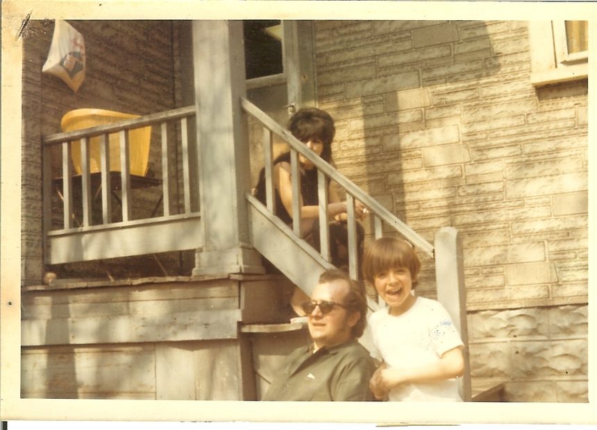 A man and a laughing boy on the back steps of a house