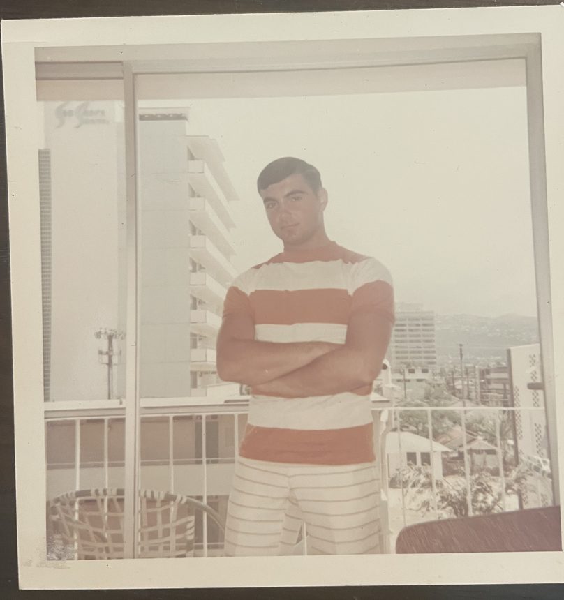 A man in a striped shirt standing with arms folded