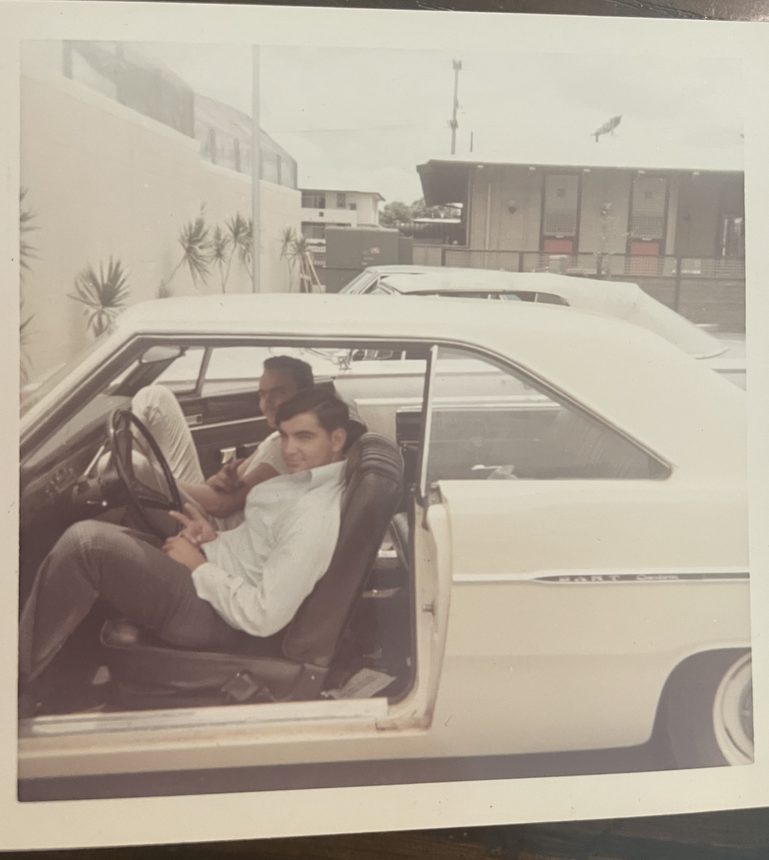 A man behind the wheel of a car with the door open