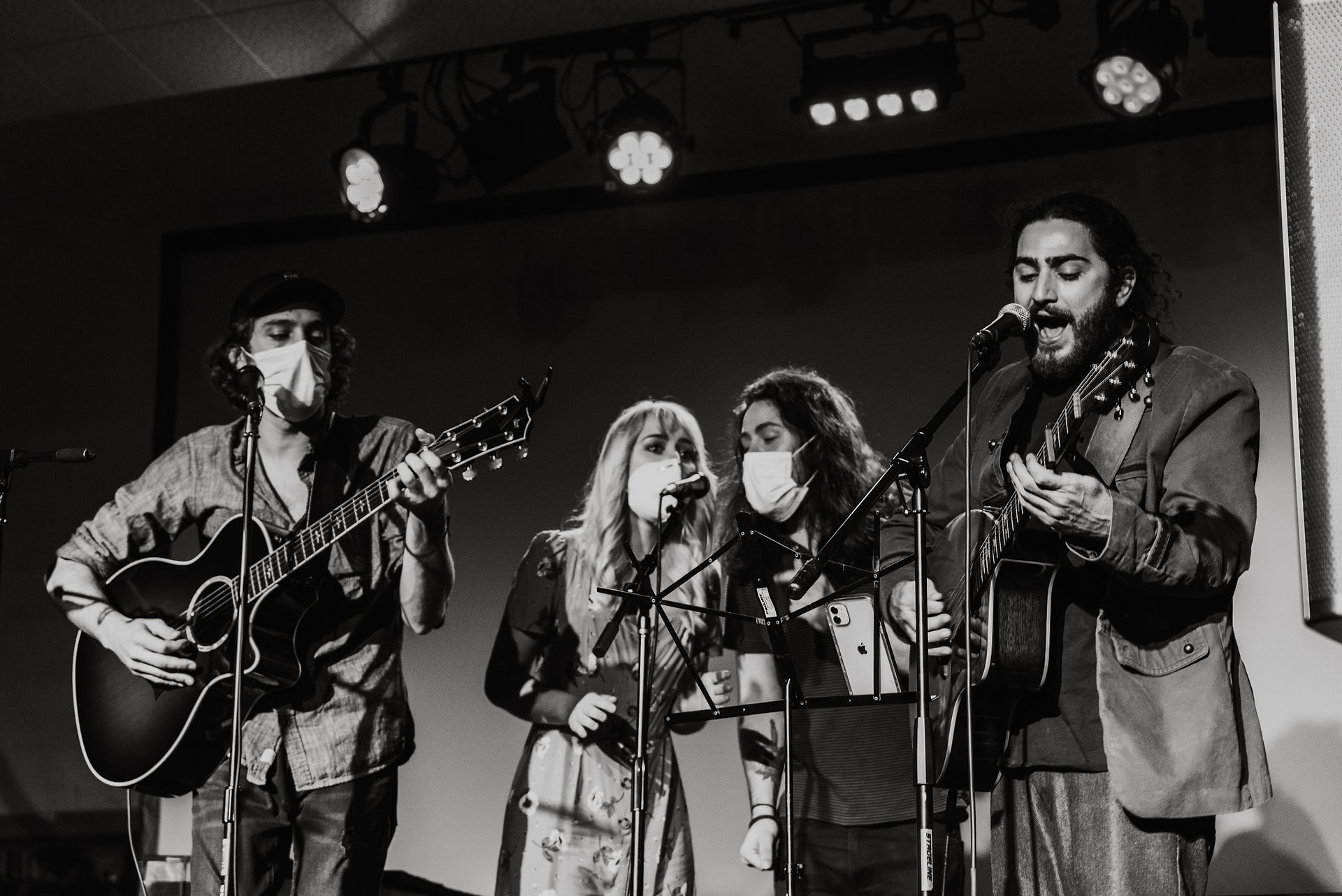 Black and white photo of group of musicians performing wearing face masks on stage