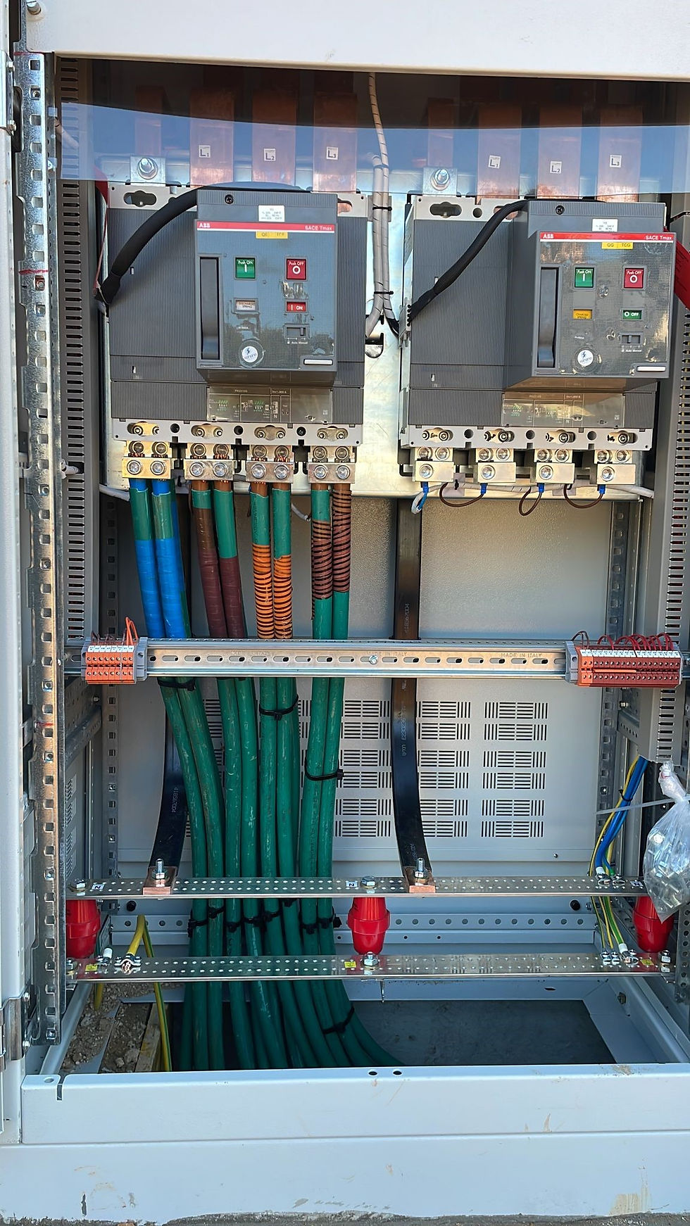 לוח חשמל תעשייתי למתח גבוה המותקן בתוך ארון מתכת אפור. הלוח מאורגן בצורה מקצועית וכולל רכיבים כבדים לניהול זרמים גבוהים בתעשייה הביטחונית