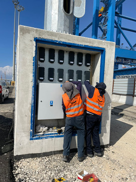 עובדי חב' עמי את יגאל מתקינים ומחברים לוח חשמל בנמל אשדוד, העובדים לבושים אפוד בטיחות