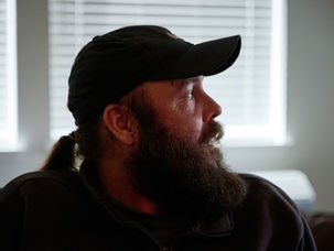 Trevor Duncan looks out the window of his Cleveland Commons apartment wearing a baseball cap.
