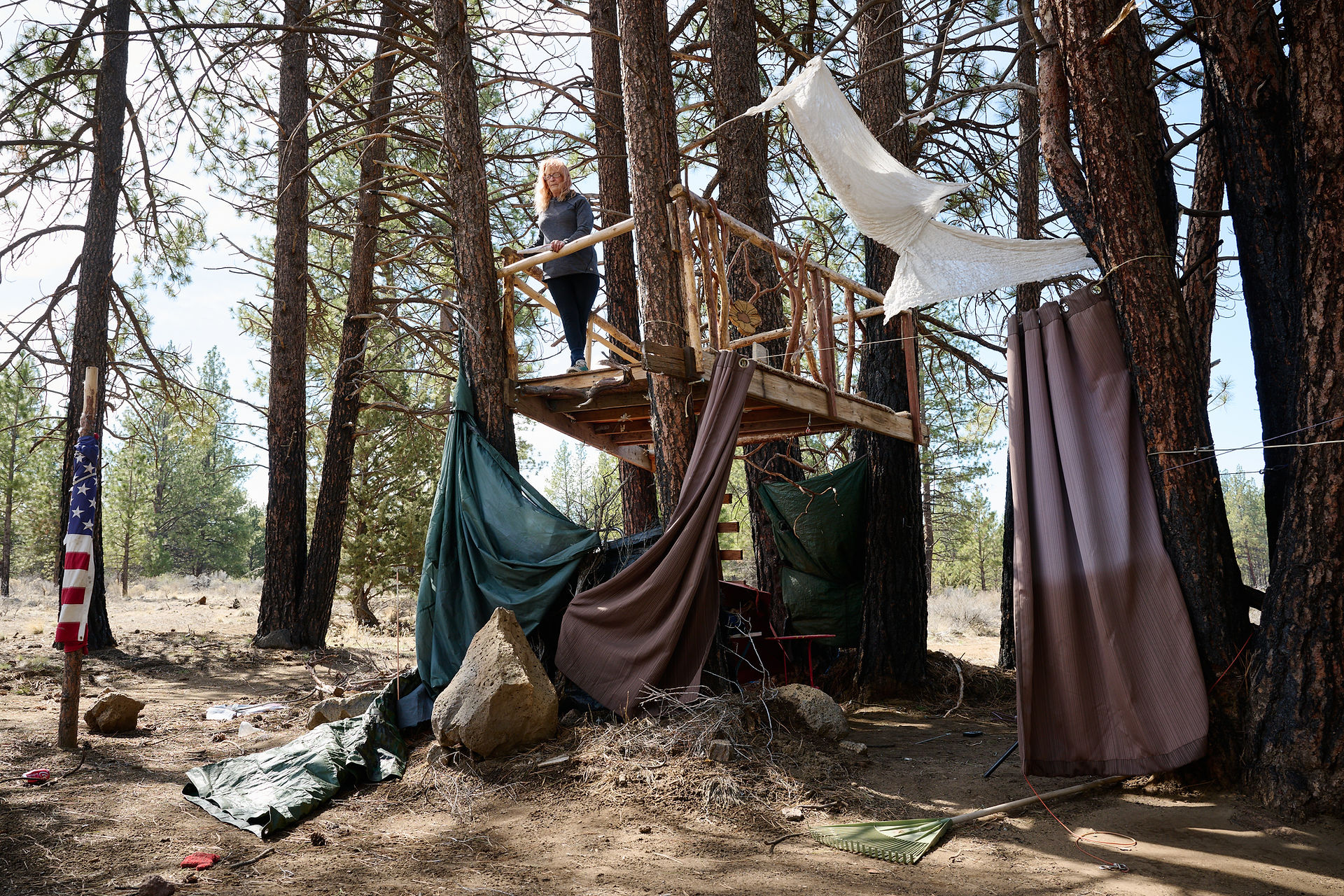 Penny Gartner looks out from the treehouse at her campsite near China Hat Road. Photo by Joe Kline.
