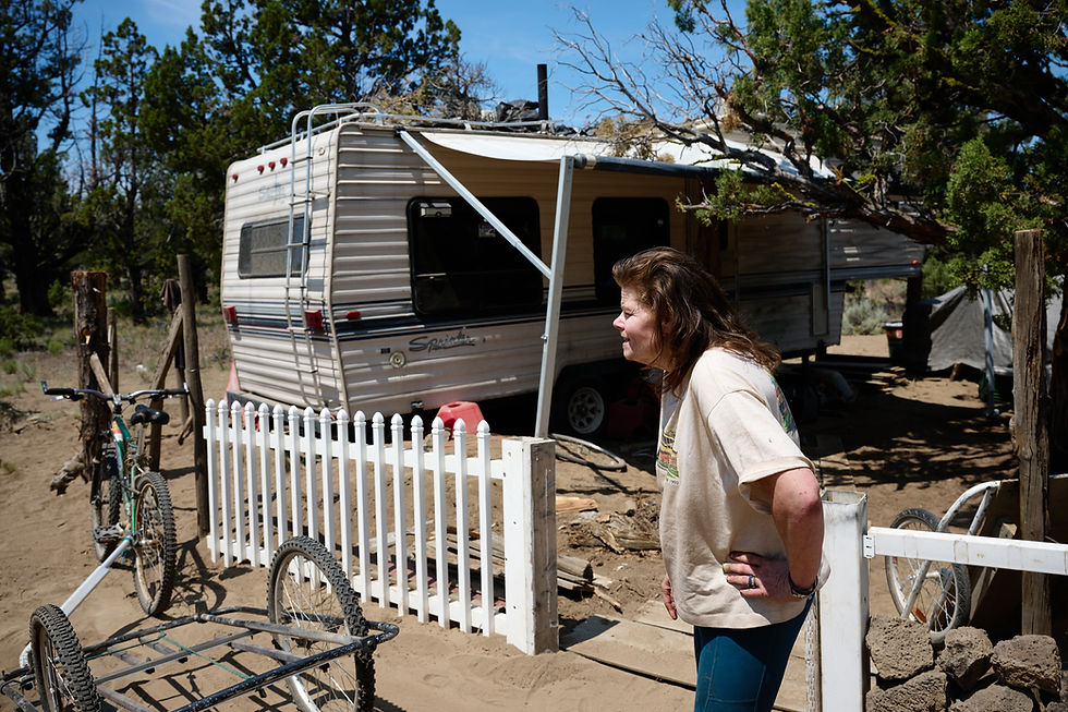 Christine Greene stands along a fence lining the outside of the camper where she and her partner live east of Bend. Photo by Joe Kline.