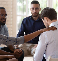 Group of individuals praying for man experiencing loss