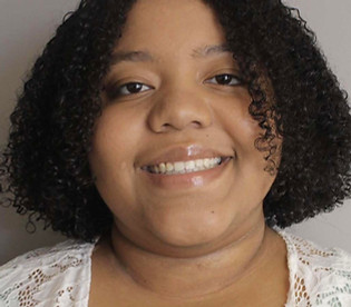 young woman with medium skin, culy chin length hair and a bright smile