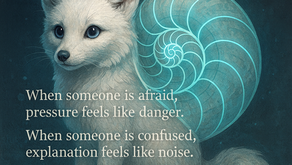 A soft, white fox with bright blue eyes sits against a deep teal background. A large glowing nautilus shell, outlined in turquoise light, spirals across its back. The fox’s tail has three small glowing blue dots near the tip. Text appears on the left side of the image in white serif font, reading: “When someone is afraid, pressure feels like danger. When someone is confused, explanation feels like noise. And when someone is overwhelmed, solutions feel like storms.” The overall tone is calm, gentle, and reflective.