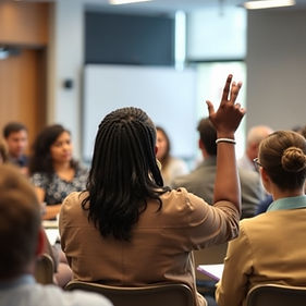 a black woman leading a workshop of about 20 people. She should be seen from the behind fo