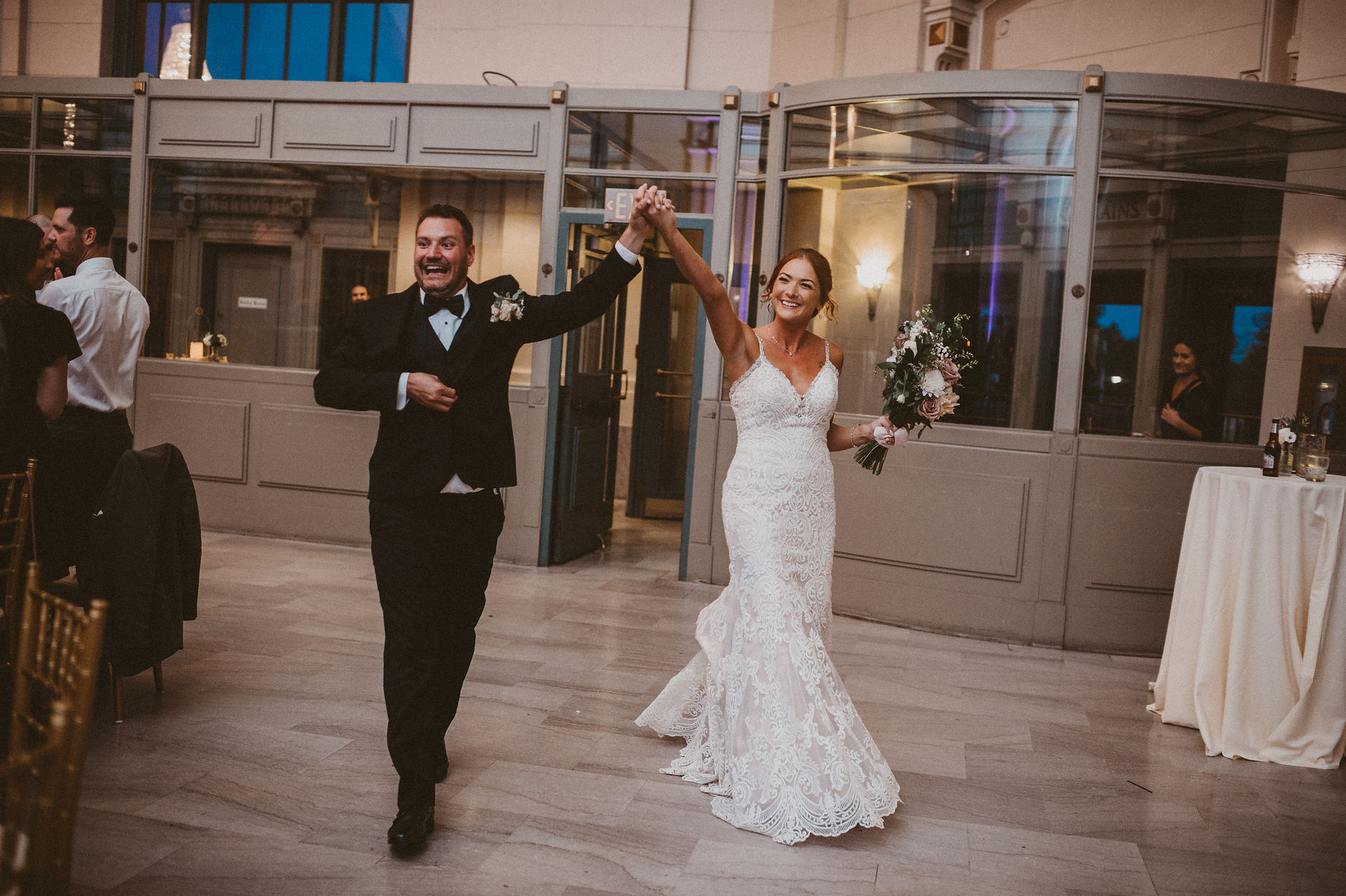 Bride and groom holding hands joyfully as they enter wedding reception