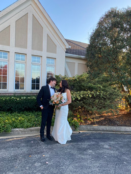 Couple standing outside of Ruffled Feathers Golf Club clubhouse smiling at each other 