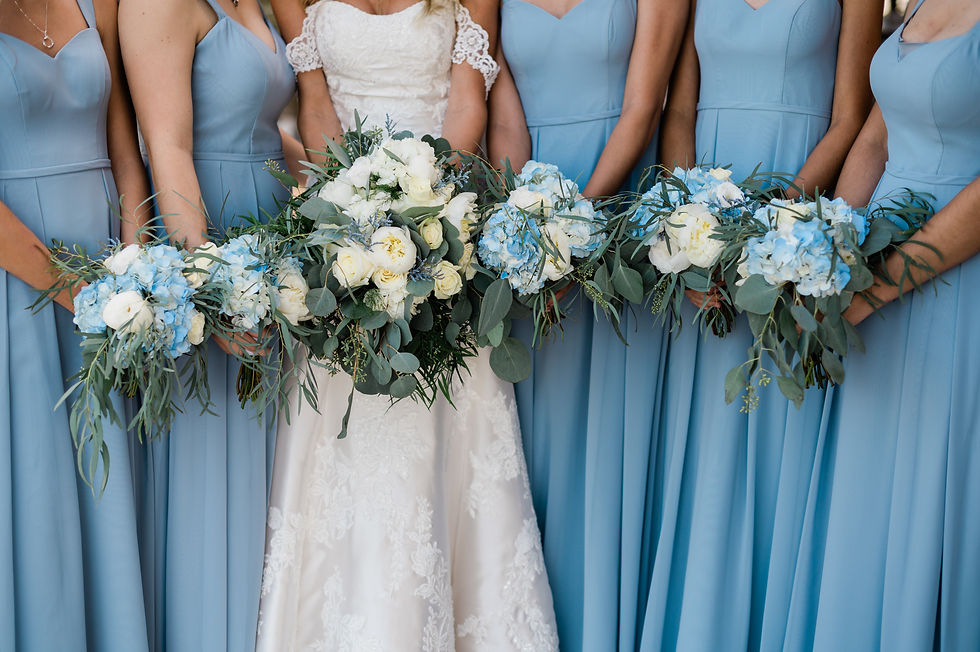White and blue bridal bouquets with eucalyptus varieties held against light blue bridesmaids' dresses