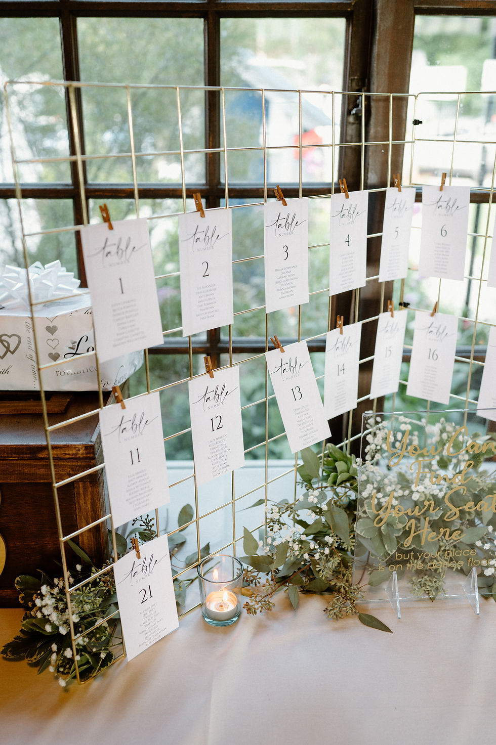 Elegant wedding seating chart with table assignment cards hung on gold wire