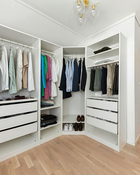 White wardrobes with open storage and drawers made to fit into a corner of the bedroom with one long wall and one short wall
