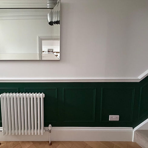 Made to measure dark green traditional wall panelling with fitted white dado rail against a crip white wall
