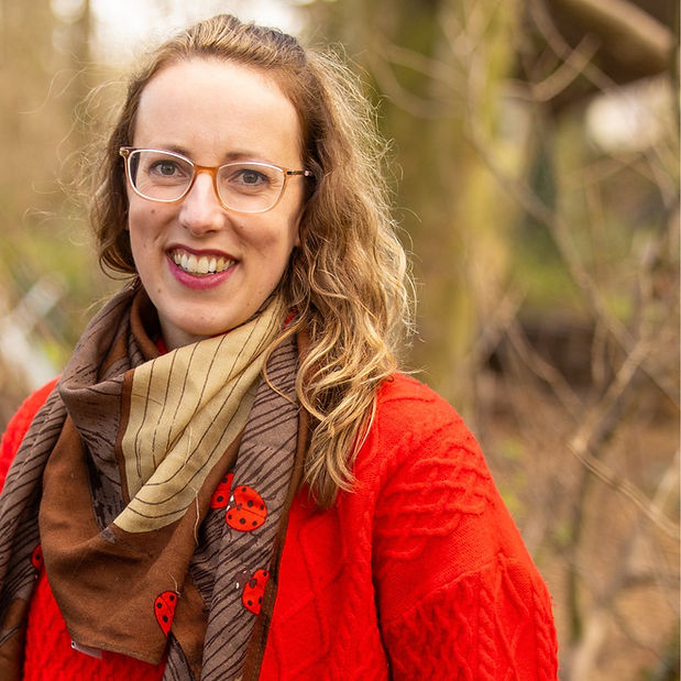 Abi Fenton in woodland wearing a red jumper and brown scarf