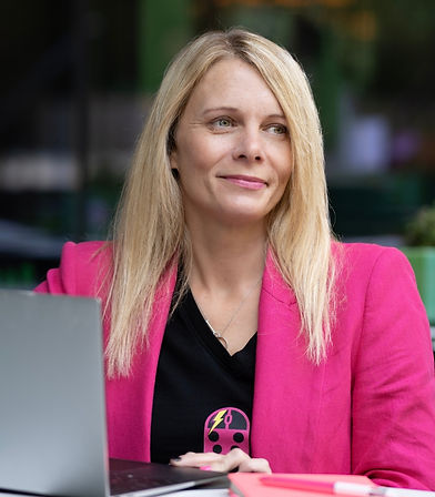 Jo from Ladybird SEO looking to the side wearing a bright pink jacket and black t-shirt with Ladybird SEO logo on it. She has long blonde hair and pink lipstick to match her jacket.