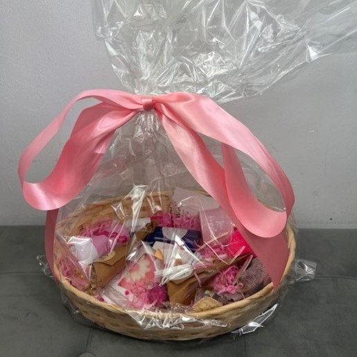A round gift basket with clear wrapping and big pink bow.