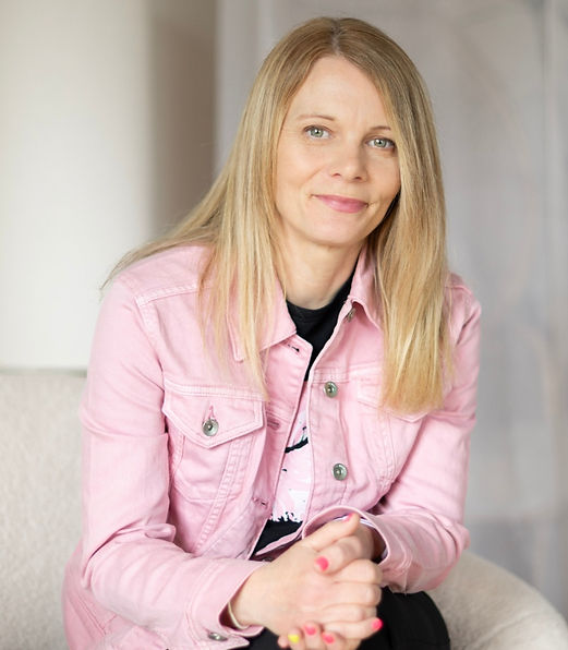 Ladybird SEO's Jo with her long blonde hair down over her shoulders, she is wearing a pale pink denim top with a black t-shirt underneath and is smiling at the camera with her mouth closed.