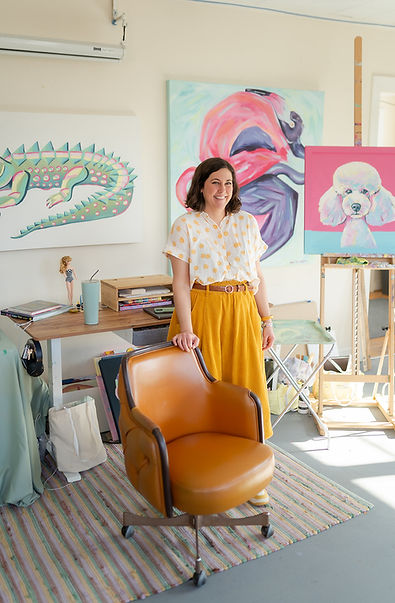 a woman standing in an art studio surrounded by colorful paintings on the wall at Activation Studios