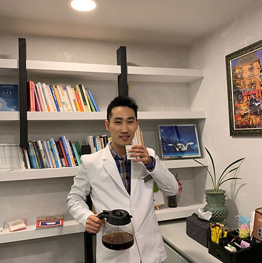 "박지훈 정신건강의학과 원장님이 병원 진료실에서 환자 상담과 진료 준비를 하고 있는 모습입니다. 전문성과 편안한 분위기가 돋보이는 병원 내부 인테리어가 환자들에게 신뢰와 안정감을 제공합니다."