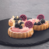 Kleine Tartes mit rosafarbener Creme, Heidelbeeren und pinken Schokoladendekoren mit Leoparden- und Zebramuster.
