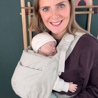 Eine Frau trägt ein Baby mit eingeklappter Kopfstütze in der Tragehilfe von Emma & Noah