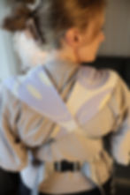 Eine Frau hat eine Tragehilfe anlegt, die am Rücken gekreuzt wird.