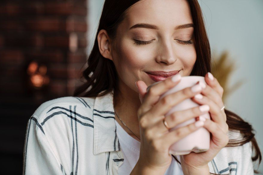 happy woman drinking and smelling to coffee