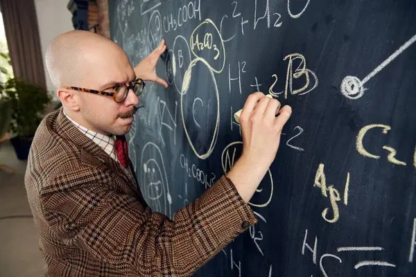 man writing on blackboard thinking and concentrated