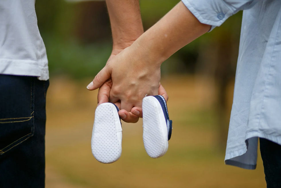 Couple holding hands and a pair of small baby shoes