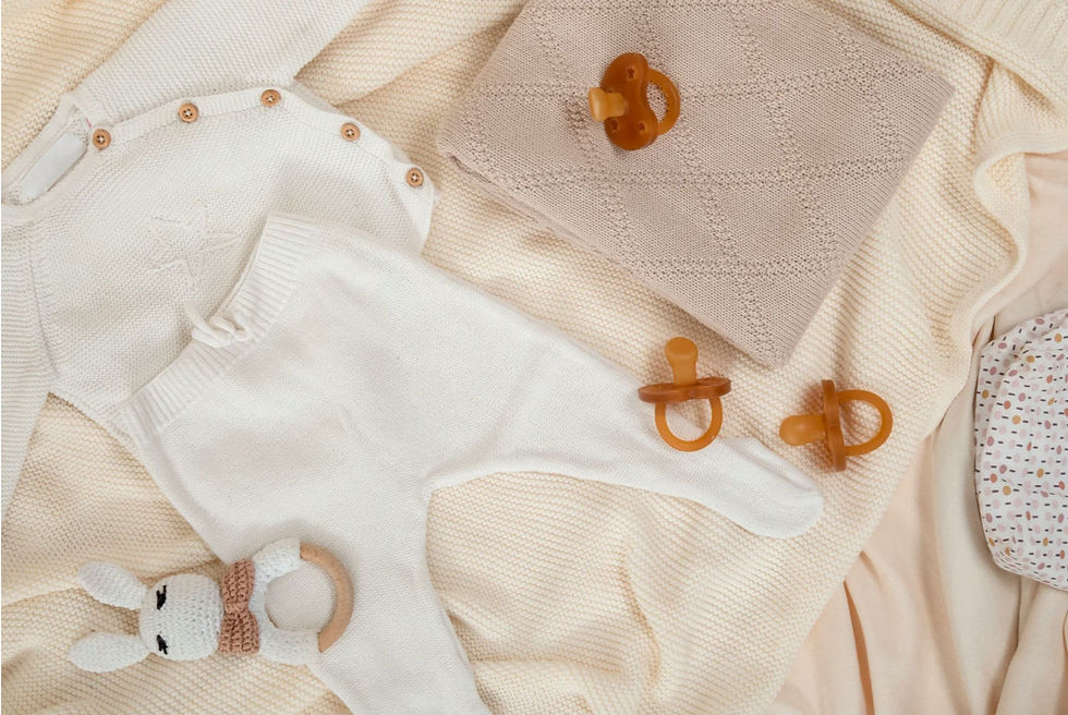 Cute white shirt and pants for baby, a toy and pacifiers for pregnancy and baby announcement