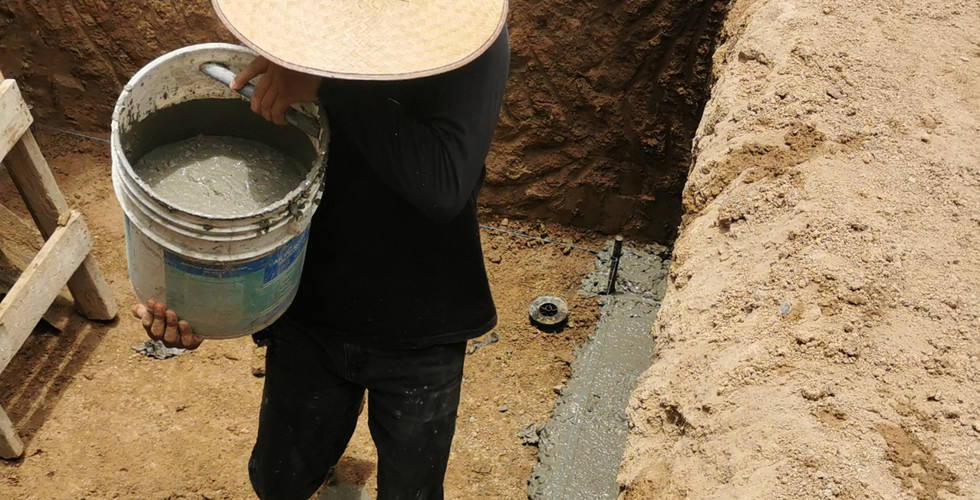 Man with hat carrying cement in a hole in the ground