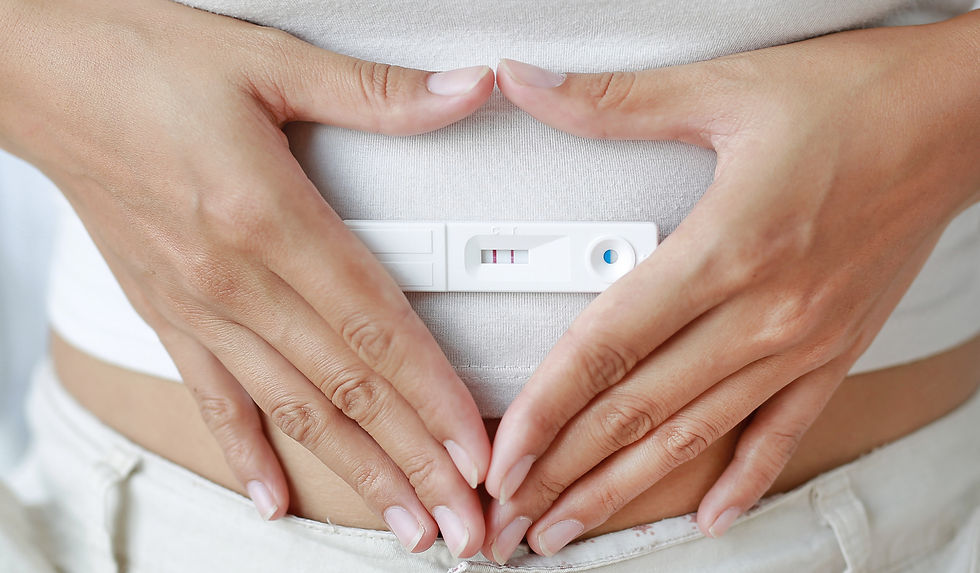 Pregnancy test with hands forming a heart on stomach