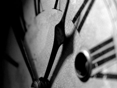 Gros plan en noir et blanc d’une vieille horloge aux chiffres romains, les aiguilles avançant sur un cadran patiné par le temps. (Source : Pinterest)