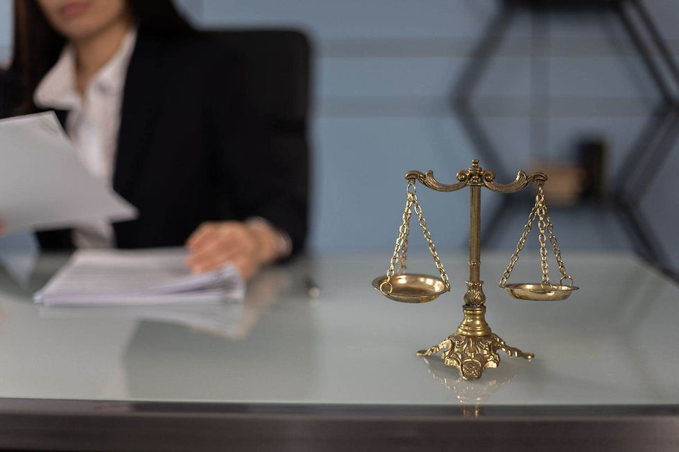A focused view of the scales of justice on the desk of a woman reviewing legal documents.