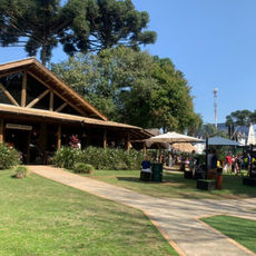 Alt Text: Área externa do Espaço Depósito, em Curitiba, com ambiente arborizado e mesas ao ar livre, destacando o restaurante como opção para celebrar o Dia dos Avós.