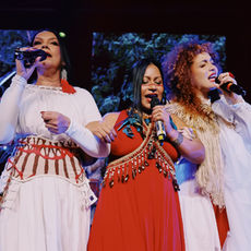 Aíla, Djuena Tikuna e Patrícia Bastos se apresentam no palco durante o espetáculo "As Amazônias", unindo música, diferentes idiomas e tradições da região Norte do Brasil.