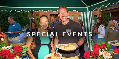 A man and woman smiling at a church dinner and holding plates of food
