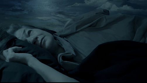 Gaia laying down with her face (left of image) looking at viewer with a sad/melancholy gaze, crying. Blue wash on image.