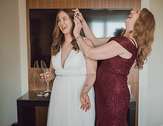 mom of bride laughing while fixing bride's hair