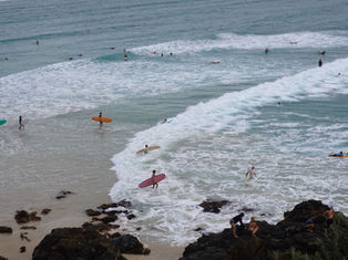 Surfers entering the water at Bondi Beach with waves rolling in, photographed for a blog about how Australia travel inspires design lovers.