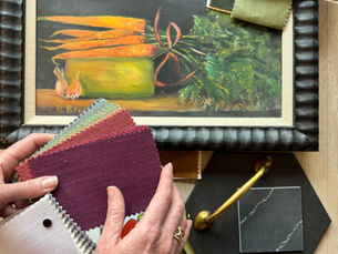 Lyn Cowie Interiors selecting fabric swatches and finishes around a client’s artwork—a framed still-life with carrots