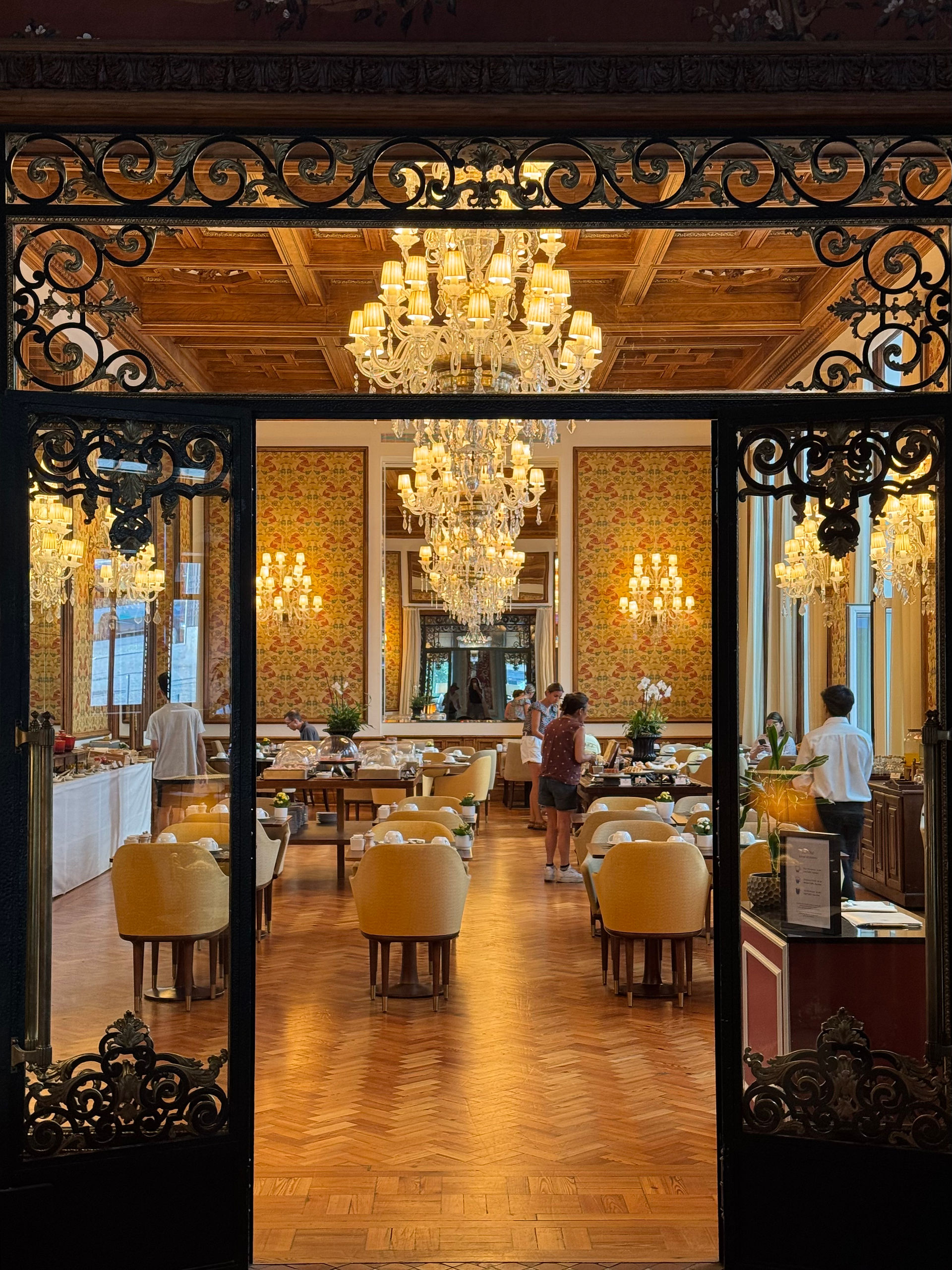 Dining room at Hospes Infante Sagres hotel with ornate ceilings, velvet chairs, and grand lighting.