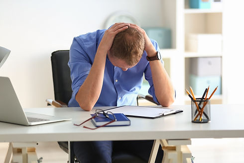 Man worried with his hands arond his neck bend over his desk