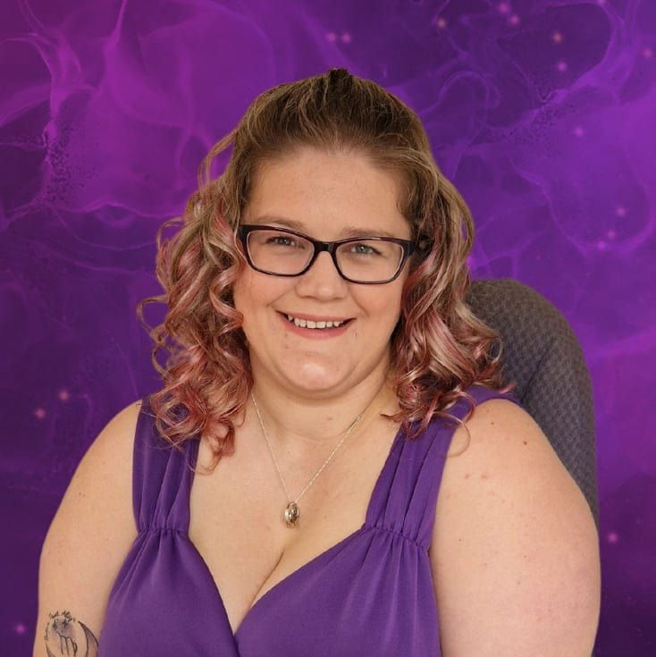 Dani Smith smiling at the camera with a purple top on and a purple background