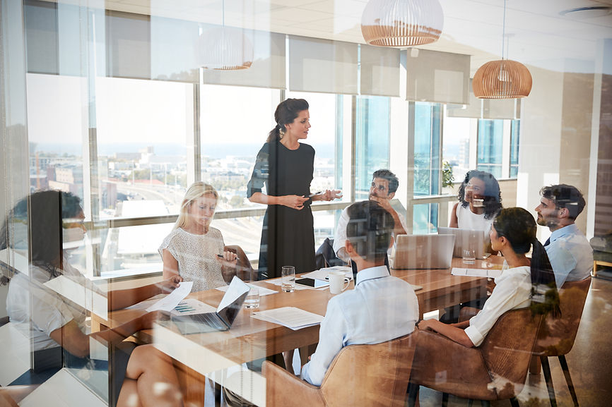 Businesswoman Leads Meeting Around Table Shot Through Door.jpg