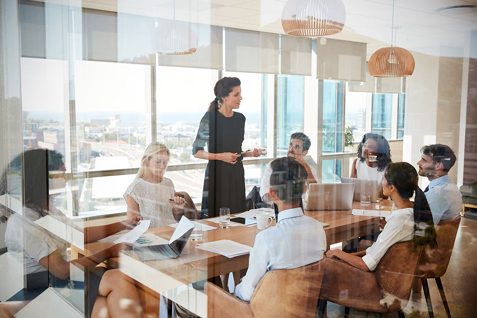 Businesswoman Leads Meeting Around Table Shot Through Door.jpg