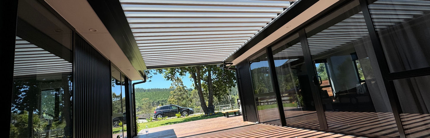 An open Skyline Louvre letting light into a long patio between two exterior walls of a house. 