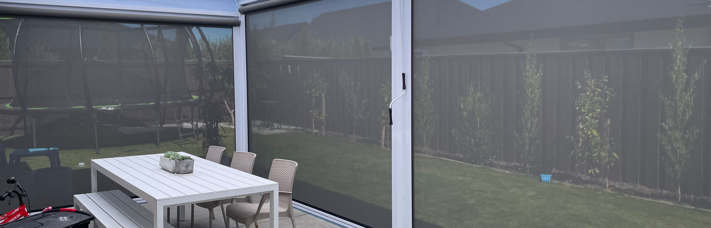 A small concrete deck surrounded by fully extended grey outdoor blinds. 